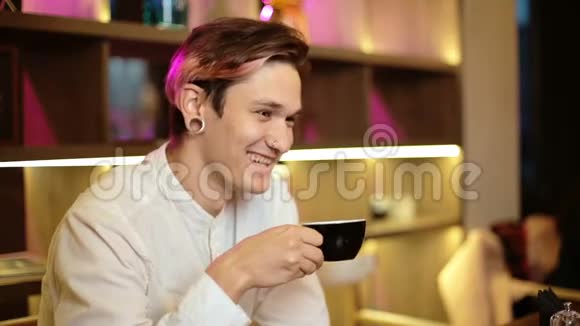 男人坐在咖啡馆里笑着笑着开心地拿着一杯黑咖啡手里拿着饮料视频的预览图