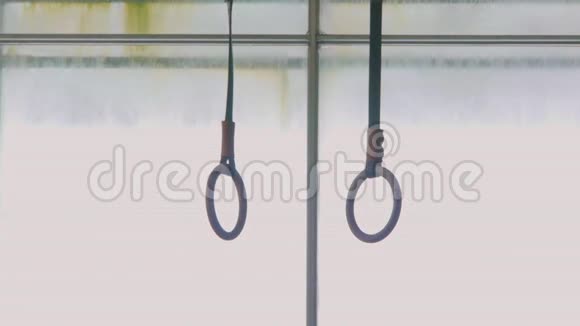 窗户背景下的体操戒指被悬挂在一个铁拱架上戒指在大厅里训练视频的预览图