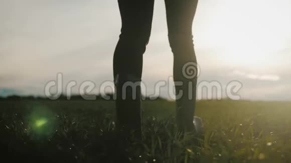 农夫带着橡胶靴沿着绿色的田野走工作用橡胶靴一个工人带着他的橡胶靴在日落时分走视频的预览图