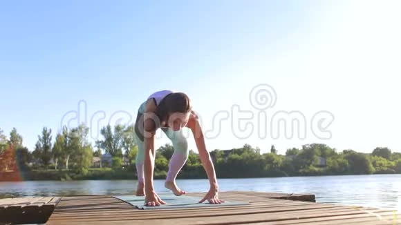 灵活的年轻女孩在一个小湖附近做瑜伽视频的预览图