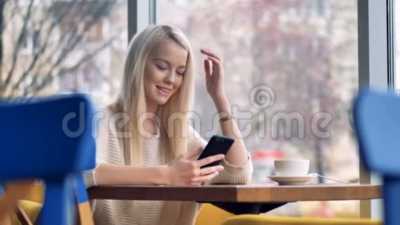 一个金发女人对她的智能手机屏幕微笑视频的预览图