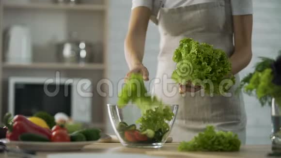 女人准备绿色沙拉撕烂它放进玻璃碗节食视频的预览图
