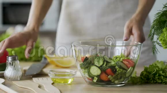 女人在沙拉里加盐在玻璃碗里加蔬菜特写视频视频的预览图