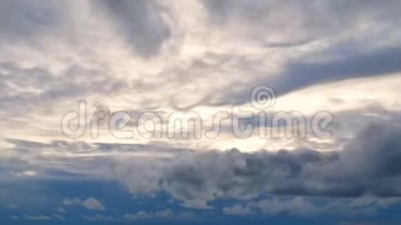 在日落或日出的时候4K片段白色蓬松的云以金色的光快速移动的蓝天视频的预览图