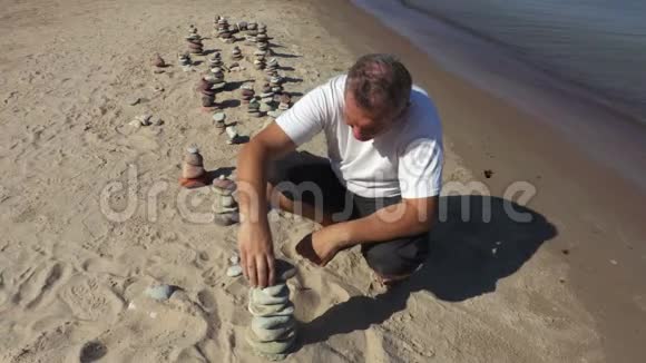 人类在海滩上建造了平衡的石头金字塔视频的预览图