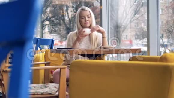 一个女人坐在咖啡馆的窗户附近支付NFC的费用视频的预览图