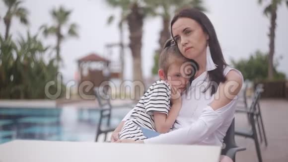 妈妈和伤心的女儿坐在泳池边的桌子旁视频的预览图