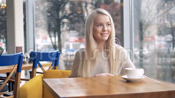 一个微笑的年轻女人在咖啡馆的桌子上支付非接触性的报酬视频的预览图