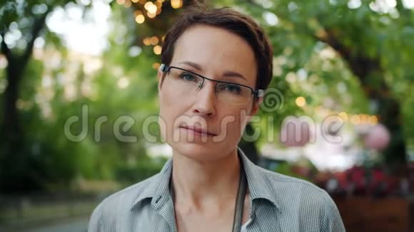夏季在户外微笑的戴眼镜的优雅女人的慢镜头肖像视频的预览图