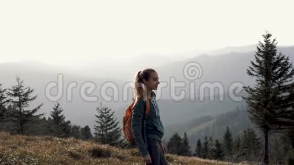 在夕阳的映衬下女徒步旅行者走在山脊的边缘视频的预览图
