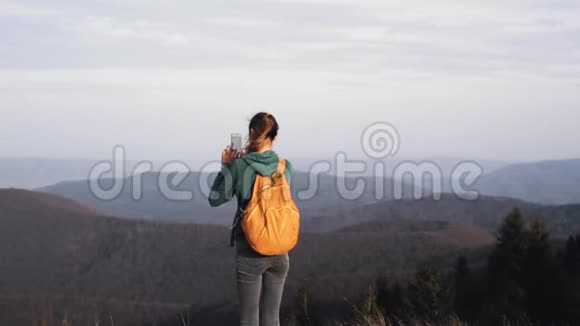 在夕阳的映衬下女徒步旅行者走在山脊的边缘视频的预览图
