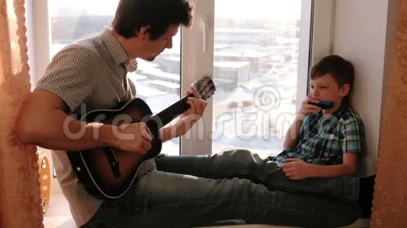 演奏乐器爸爸在弹吉他儿子坐在窗台上弹口琴视频的预览图