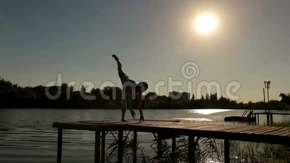 在小湖上练瑜伽的运动女孩剪影视频的预览图