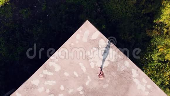 做瑜伽的年轻女人废弃房子的屋顶从上面看从无人机上移走视频的预览图