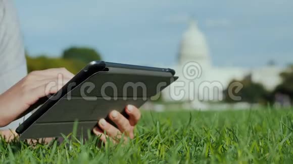 在国会大厦的背景上使用平板电脑在框架中你只能看到手旅游学习和旅行视频的预览图