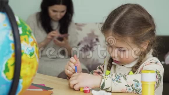 漂亮的小女孩正坐在家里的桌子上画一个泥工视频的预览图