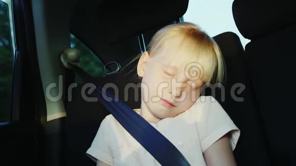 女孩6岁坐在汽车后座上系着安全带睡在路上视频的预览图