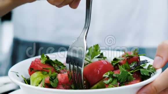 女人在餐厅的特写镜头里吃黄瓜和西红柿的生叉沙拉视频的预览图