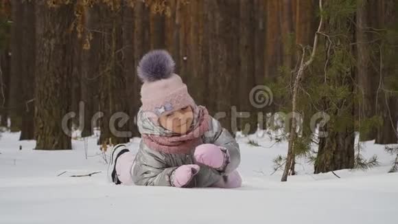 可爱的小女孩在冬天的森林里爬雪视频的预览图