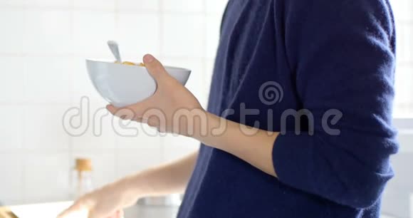 男子使用数码平板电脑同时享用一碗早餐麦片视频的预览图