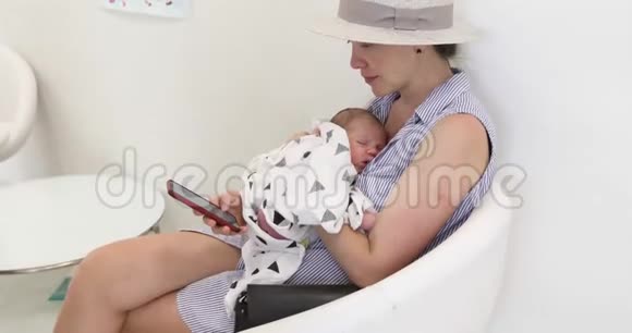 有宝宝的女人用智能手机视频的预览图