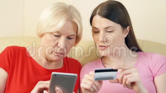母女俩在智能手机上用信用卡在线购物老年人使用技术视频的预览图