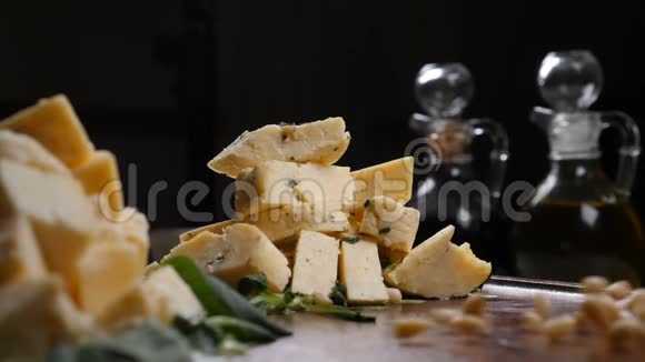 餐厅艺术概念不同种类的奶酪放在黑色背景上的堆里手中的松子慢动作视频的预览图