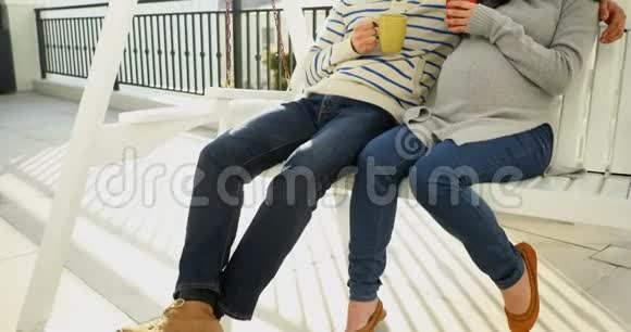 怀孕夫妇坐在秋千上喝咖啡视频的预览图
