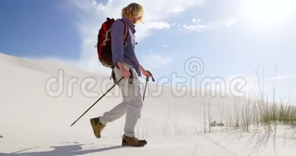 带着登山杆在沙漠中行走的人视频的预览图