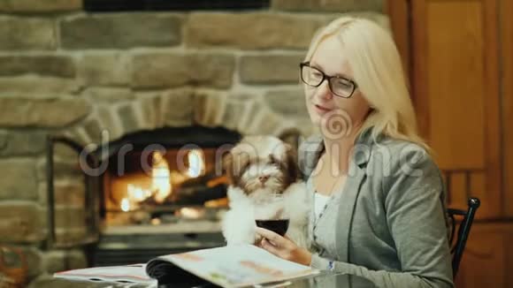 一个女人正在品酒坐在壁炉附近的一家餐馆里他手里拿着一只小狗视频的预览图