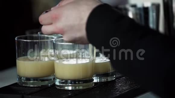 穿黑色衣服的侍者从酒吧摇床上把软饮料倒入玻璃杯里视频的预览图