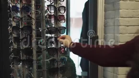 女人正在商店里转着一个带着时髦太阳镜的展台的景色视频的预览图