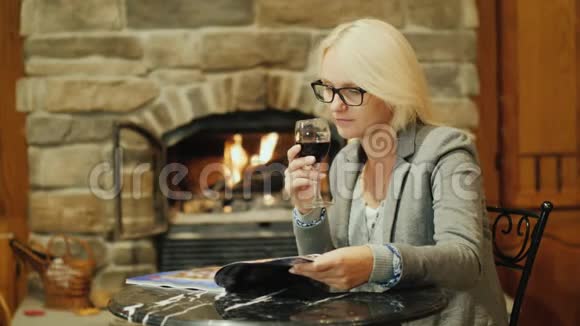 一个拿着一杯红酒的女人正在餐厅休息看着桌上的杂志视频的预览图