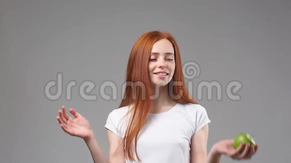 年轻的红头发女孩扔绿色苹果慢动作视频的预览图