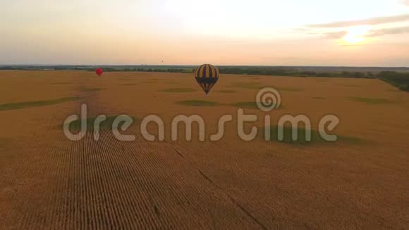 黄昏时分两个热气球漂浮在田野上对着炽热的天空视频的预览图