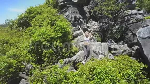 Flycam摆脱女孩在岩石上的姿态并展示海洋湾视频的预览图