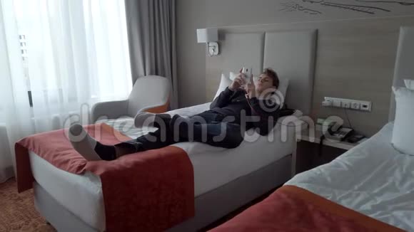 年轻人躺在旅馆房间的床上视频的预览图