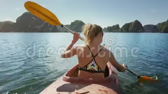 穿比基尼的背景女孩划皮划艇去海湾的岛屿视频的预览图