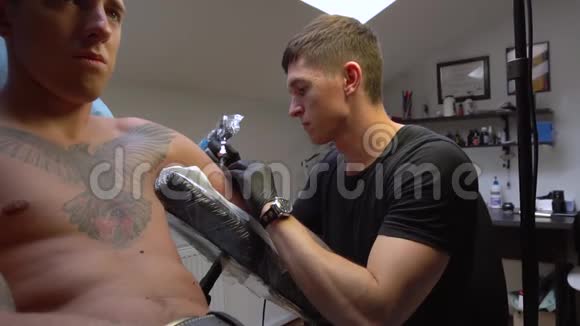 成年男子在纹身师给他带来不适和轻微疼痛时会勇敢地受苦视频的预览图