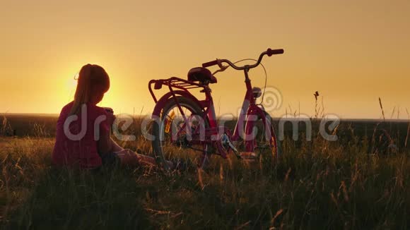 这个女孩6岁坐在自行车附近使用智能手机日落时风景如画的地方视频的预览图