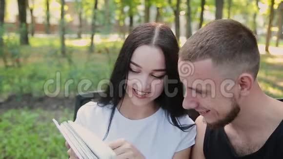 两个情人坐在长凳上互相微笑着看家庭照片视频的预览图