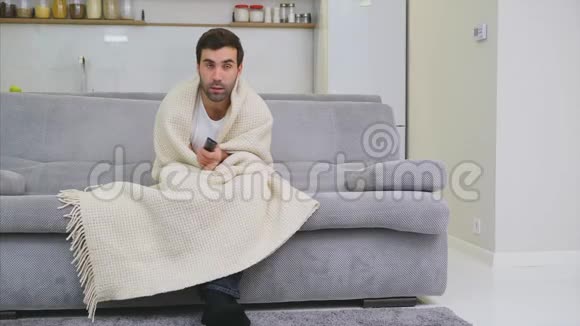 年轻夫妇在公寓里放松躺在沙发上看电影盖上毯子快乐视频的预览图