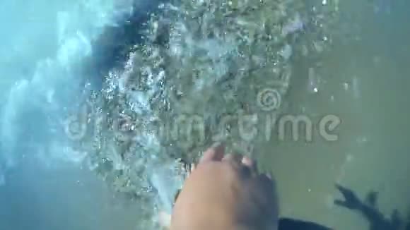 女孩的手躺在贝壳沙滩上海浪在滚动特写视频的预览图