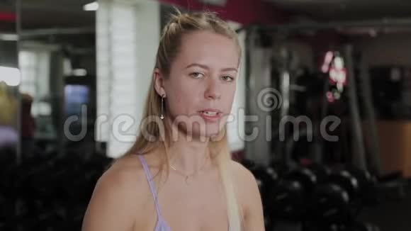 有着美丽身材的运动女人女孩在健身房的模拟器上训练二头肌视频的预览图