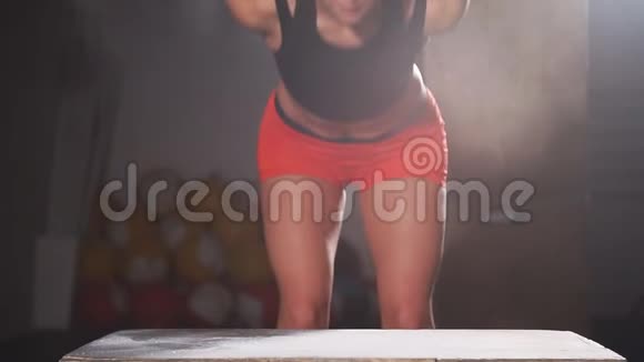 运动的年轻女人在交叉训练的健身房里跳过一些盒子慢动作视频的预览图