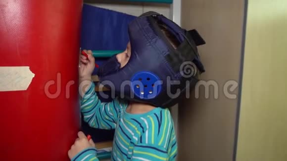 戴拳击头盔的男孩用毛毡尖笔在拳击袋上划拳视频的预览图