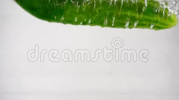 绿色的新鲜黄瓜在白色的背景下落入水中视频的预览图