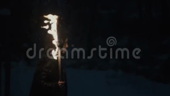一个年轻的神秘女人拿着火炬在黑暗的森林里行走的肖像视频的预览图