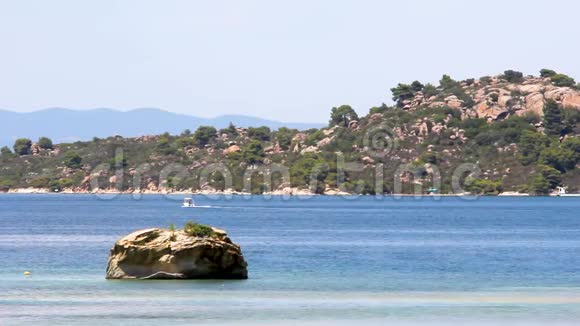 一个田园诗般的海滩和一艘快艇穿过它海边的岩石和树木希腊哈尔基迪基视频的预览图