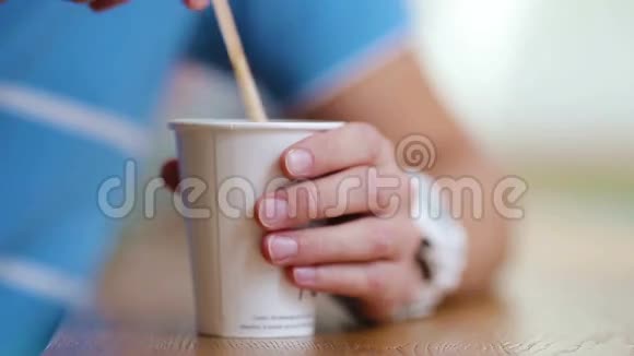 男性手的特写镜头在咖啡馆里用咖啡搅拌杯子里的糖视频的预览图